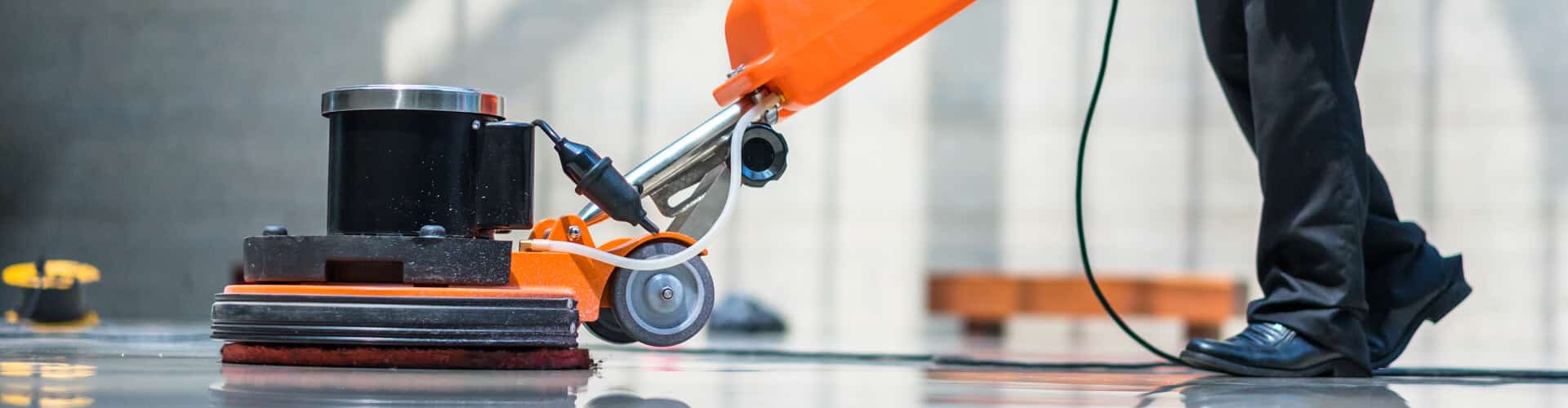 Mand udfører gulvpolering med orange maskine